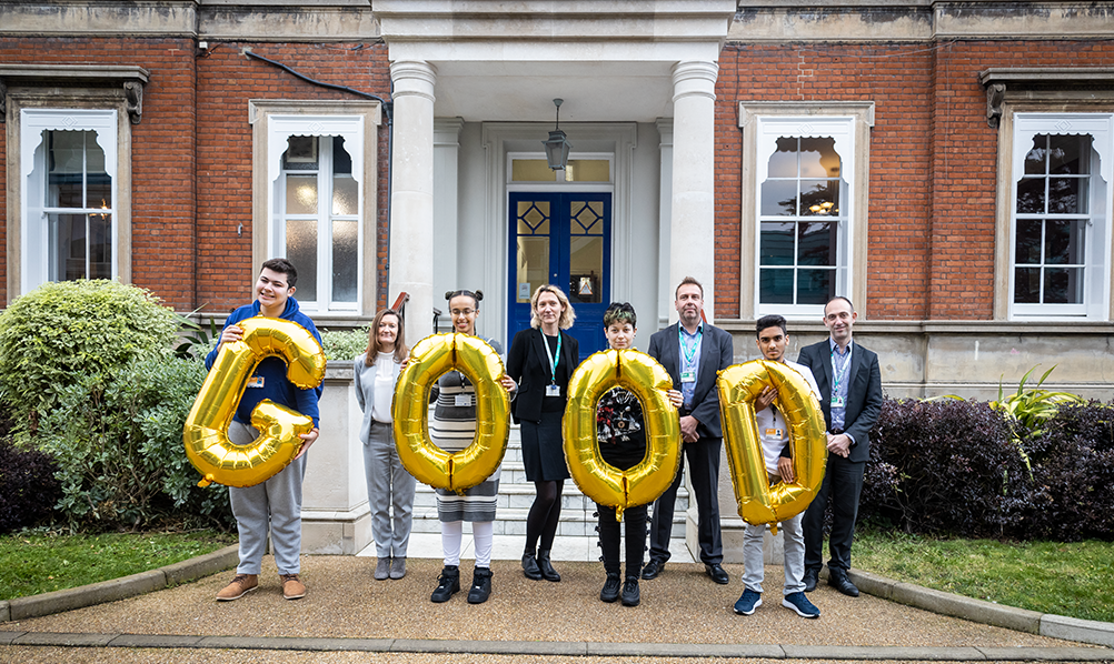 Students and executive team hold up individual letters that says 'Good'